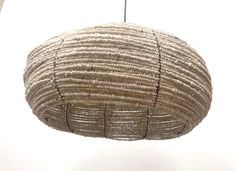 a large woven ball hanging from a ceiling in a room with white walls and flooring