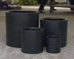 three black vases are sitting on the ground