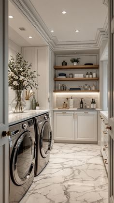 a washer and dryer in a room with white cabinets, marble flooring