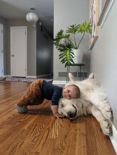 a young boy laying on the floor next to a large white dog