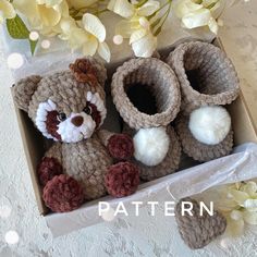 a crocheted teddy bear and booties in a box with flowers on the side