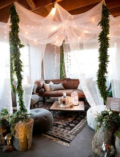 a living room filled with furniture covered in white curtains and greenery on the ceiling