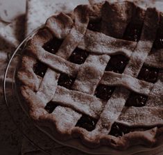 an apple pie is covered in powdered sugar and sits on a glass platter