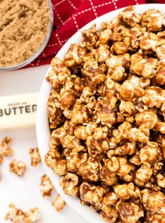 a white bowl filled with caramel popcorn next to a spoon