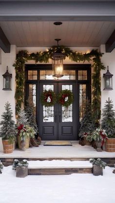 the front door is decorated for christmas with wreaths and potted trees