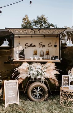 an old fashioned food truck is decorated with flowers and signs for guests to sit in