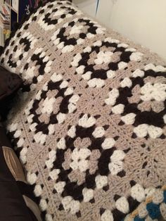 a crocheted blanket on top of a couch next to a book shelf filled with books