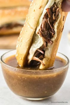 a sandwich being dipped with chocolate sauce in a glass bowl