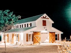 a white barn at night with lights on