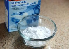 a glass bowl filled with baking soda next to a carton of baking soda on a counter