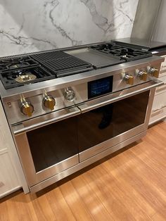 a stainless steel stove with two burners and one oven door open on a wooden floor