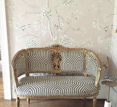 a couch sitting on top of a hard wood floor next to a wall with flowers