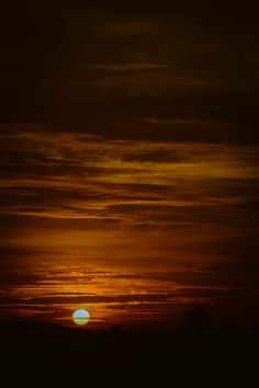 the sun is setting behind some clouds in an orange and black sky with no one on it