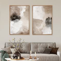 two paintings on the wall above a couch in a living room with coffee table and candles