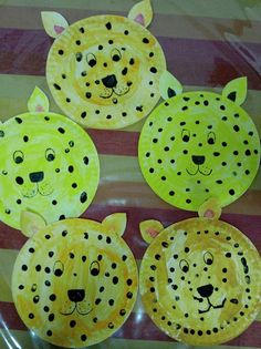 three paper plates that have animals on them and one is painted yellow with black dots