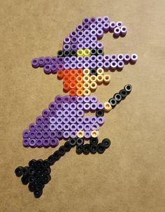 a purple and black beaded witch on a brown surface