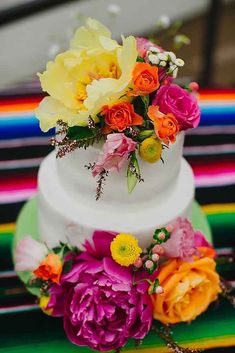 a multi - colored wedding cake with flowers on top