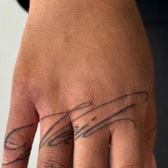 a person's hand with a tattoo on it and the ring finger is in black ink