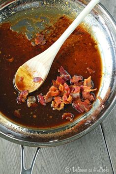 a wooden spoon is being used to stir food in a bowl with bacon on the side