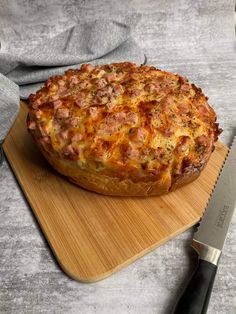 a pizza sitting on top of a cutting board next to a knife