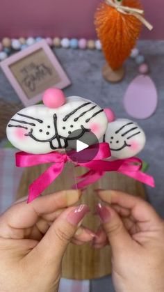 someone is holding a cake decorated like a cat in front of a table with other decorations