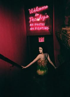 a woman standing in front of a neon sign