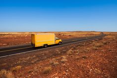 a yellow truck is driving down the road in the middle of an open desert area