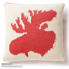 a red and white knitted moose pillow