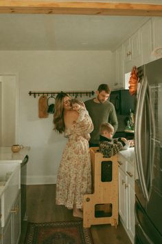 a man and woman standing in a kitchen with a toddler on the counter next to them