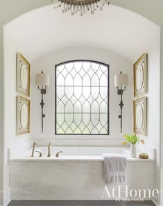 a bath room with a large window and a tub under a light hanging from the ceiling