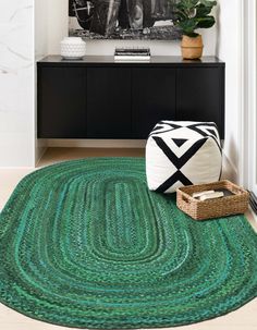 a green rug is on the floor in front of a black and white photo with a basket