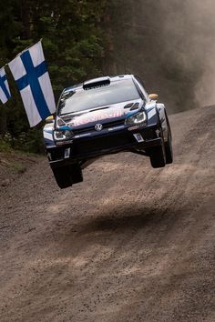 a car is jumping over a dirt road with a flag on it's side