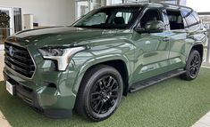 the front end of a green toyota pickup truck in a showroom with large windows