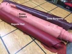 two pieces of leather sitting on top of a wooden floor next to a red piece of cloth