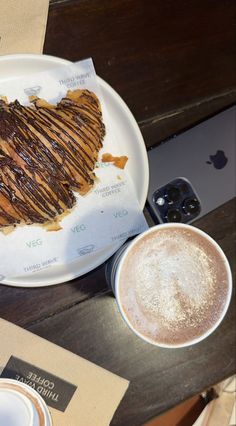 a heart shaped piece of bread on a plate next to a cup of coffee and an apple