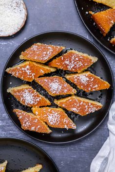 several slices of cake on black plates with powdered sugar