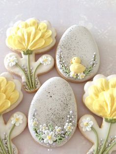 decorated cookies with yellow flowers and birds on them are arranged in the shape of eggs