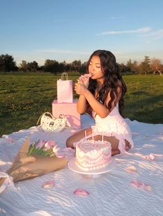 a woman sitting at a table with a cake in front of her and a pink gift bag