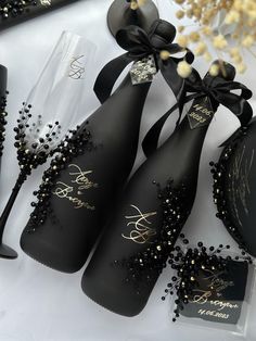 three black bottles with gold designs on them sitting next to some wine glasses and other items