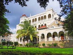 a large white building surrounded by lush green trees