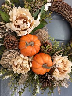 two pumpkins are sitting on top of a wreath