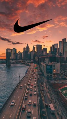 an aerial view of a city at sunset with a nike logo above the highway and cars on the road