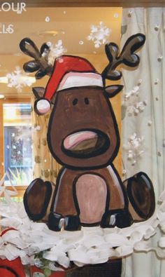 an image of a christmas reindeer in the window with snow falling all around him and behind it is a sign that says collour my walls