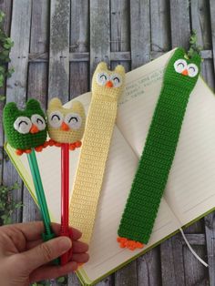 an open book with three crocheted owls on it and two pencils in front of them