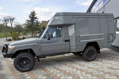 an off road vehicle parked in front of a building on a brick floored driveway