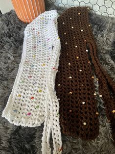 two crocheted scarves sitting on top of a rug