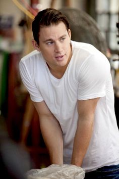 a man in white shirt and jeans leaning over a table