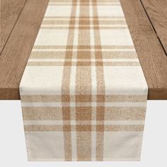 an image of a table runner on top of a wooden table with white and tan plaid