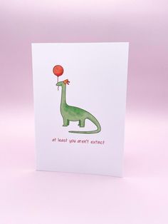 a card with an image of a dinosaur holding a red balloon on it's head