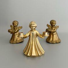 three golden angel figurines on a gray surface